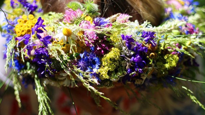 Zdjęcie przedstawia głowę kobiety z nałożonym wiankiem z kwiatów.
